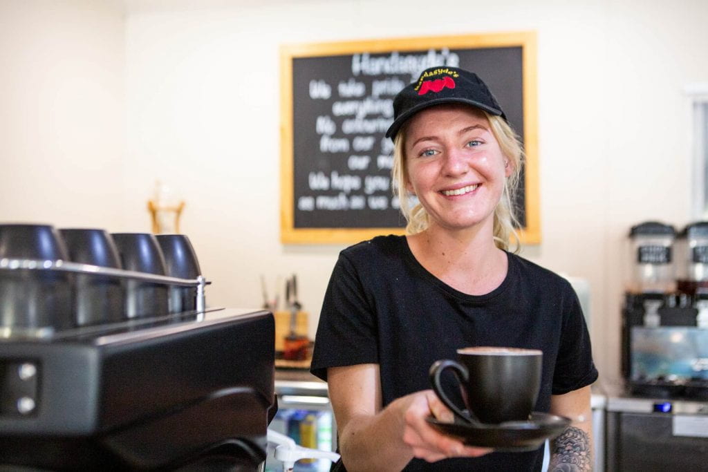 Smiling young woman handing you a coffee